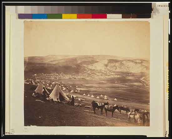 Cavalry camp near Balaklava. Military encampment showing conical tents, people, and horses, with mountains in the background.